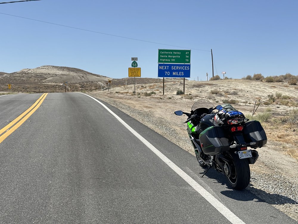 2025 Kawasaki H2 SX SE parked on the side of California Route 58, with road signs showing 70 miles to next services.