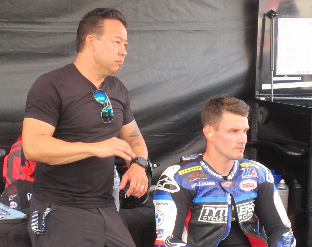 Jake Zemke with Cameron Beaubier in his leathers watching the timing monitor in the pits at the race