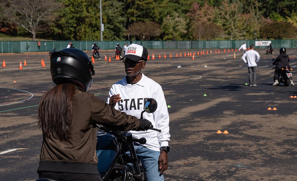 instructor explaining a point to a woman student sitting on a motorcycle