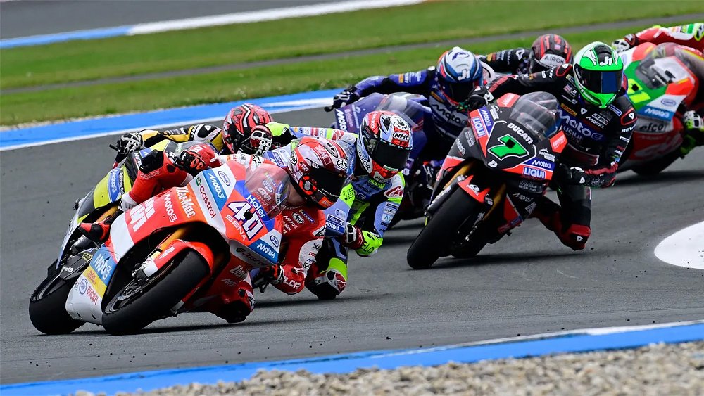 A pack of MotoE riders lean into a corner on the race track.