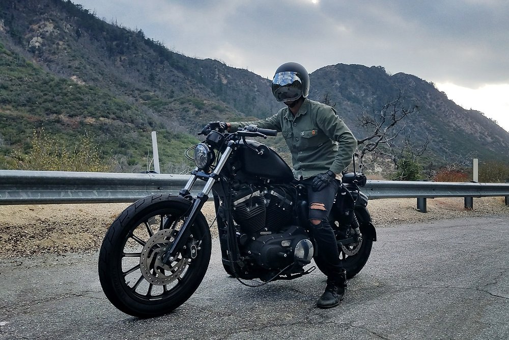 Dustin wearing torn jeans and a green military shirt on a black Sportster