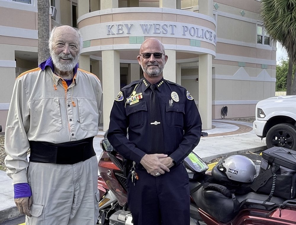 Daub posing in front of the Key West Police Station with his motorcycle and the chief of police