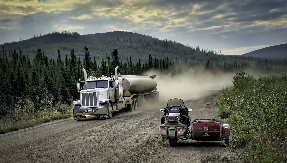 Gold Wing and sidecar parked along the remote dirt road as a truck roars past spraying dust