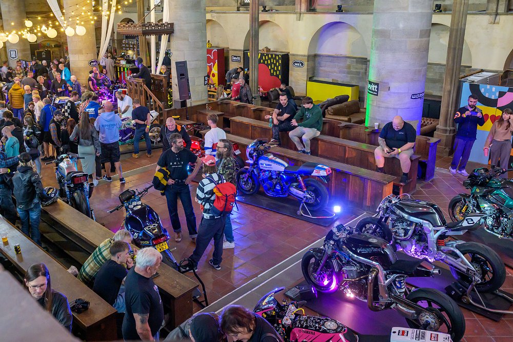 overview photo of the scene inside the old church with visitors looking at motorcycles on display