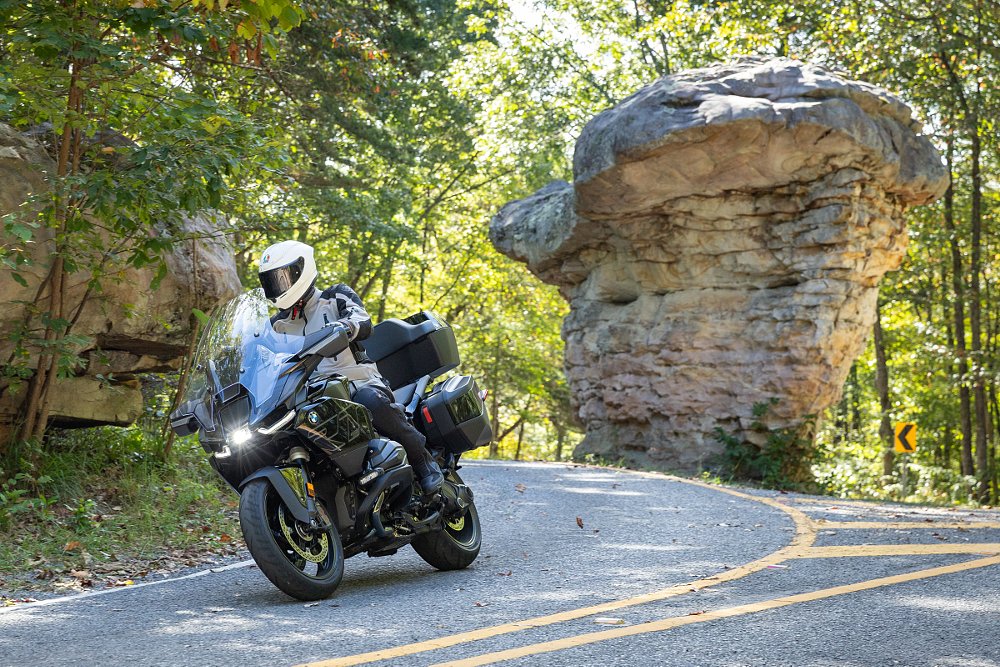 rider going past a tall rock where the road splits apart to go around it