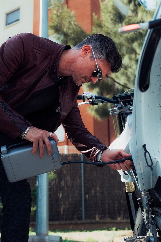 A Stark VARG SM owner plugs a portable charger into the bike.