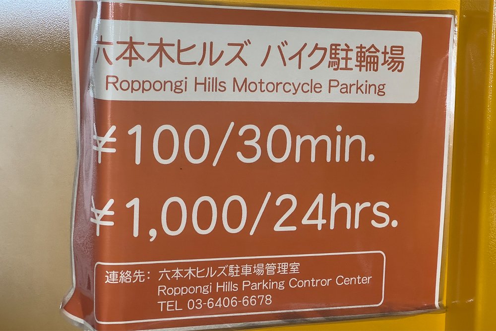 A sign displays the rates for a motorcycle parking lot.